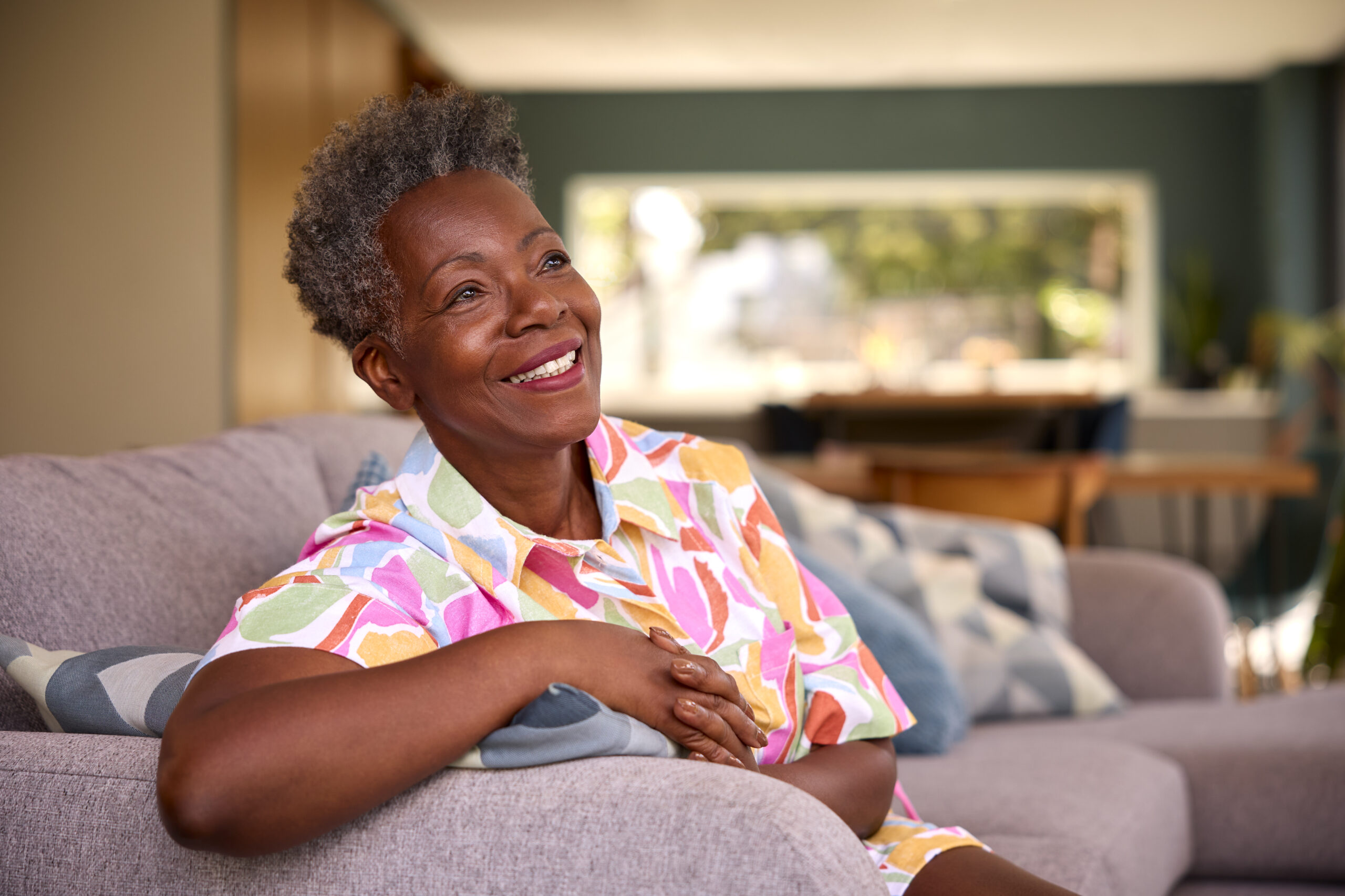 Portrait Of Retired Smiling Senior Woman Relaxing On Sofa At Home